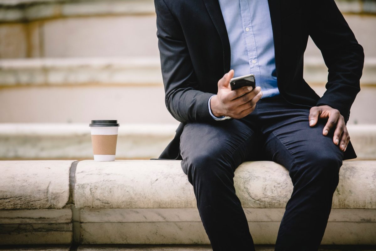 A Guide to The Complex World of Business SMS Texting Regulations. Image of man sending texts on a mobile phone