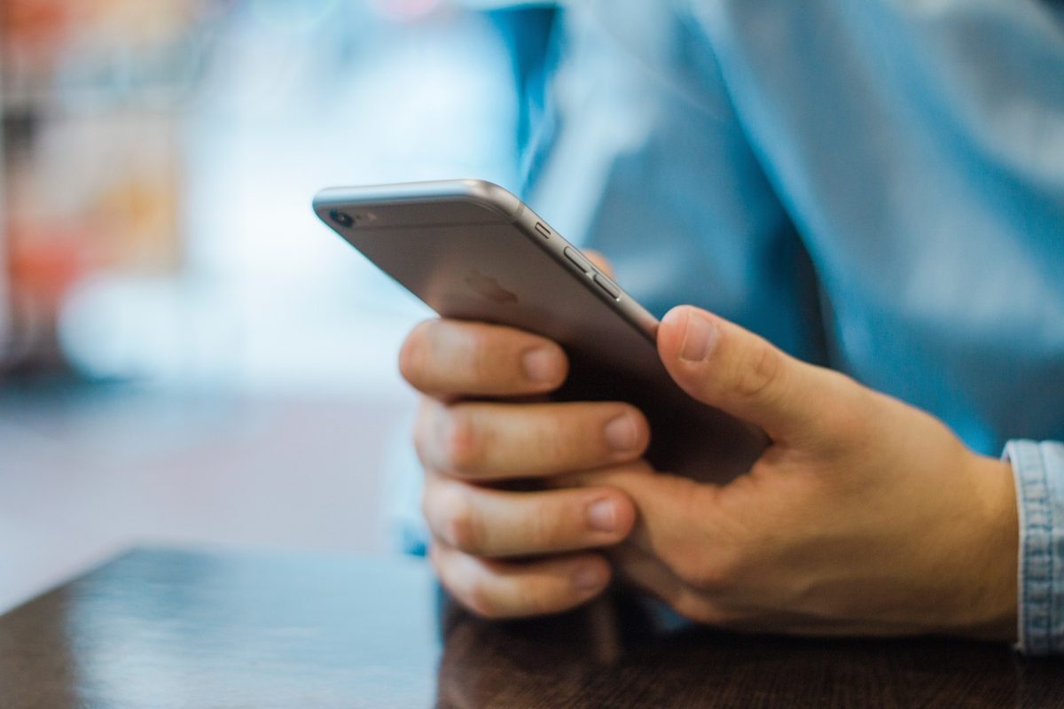 What are the differences between business and mobile SMS texting? Image of man sending texts on a mobile phone