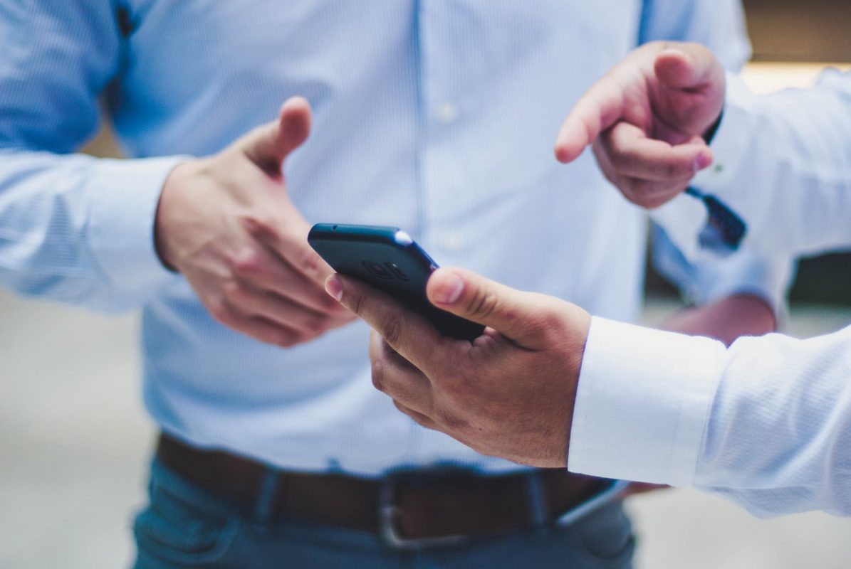 Preparing your business for an emergency with cloud-based, unified communications. Image of two men discussing a mobile phone